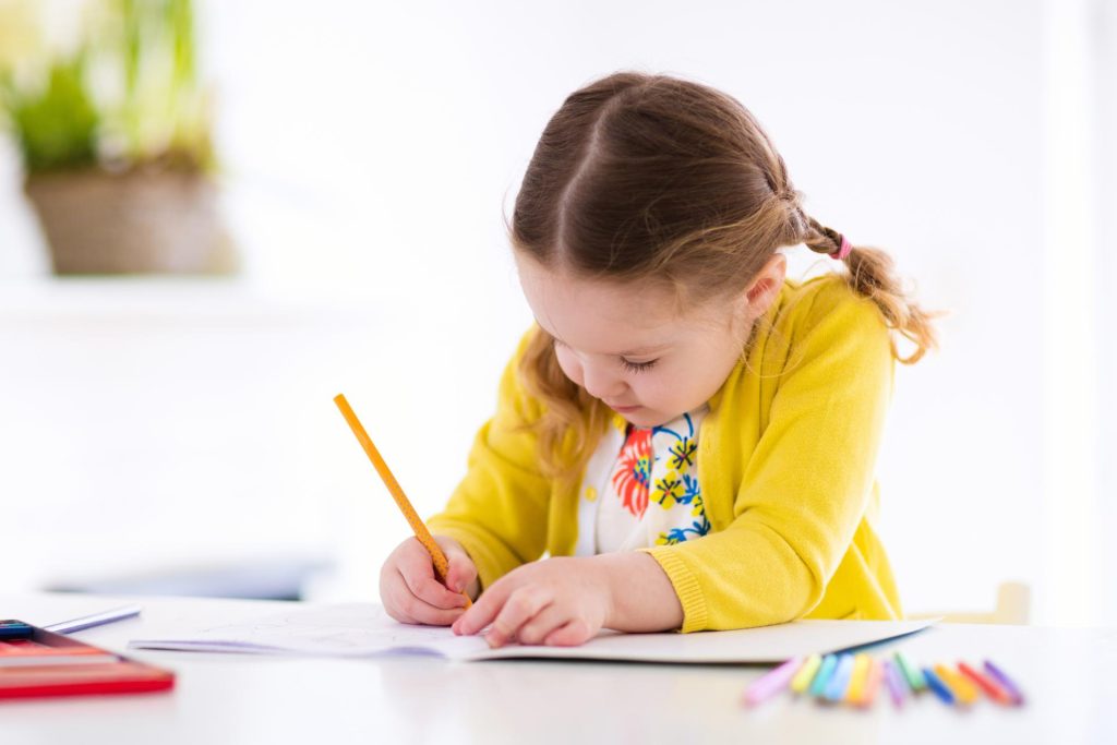 Little girl drawing on her desk